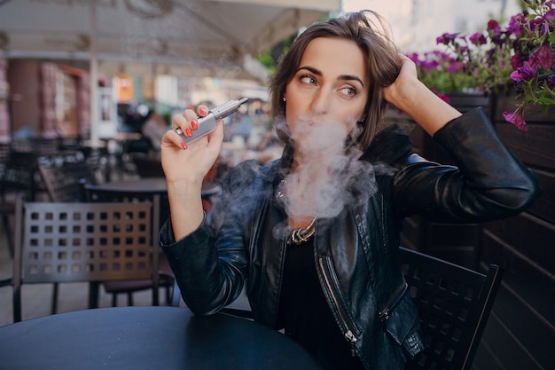 Женщина мышления с электронной сигаретой в руке