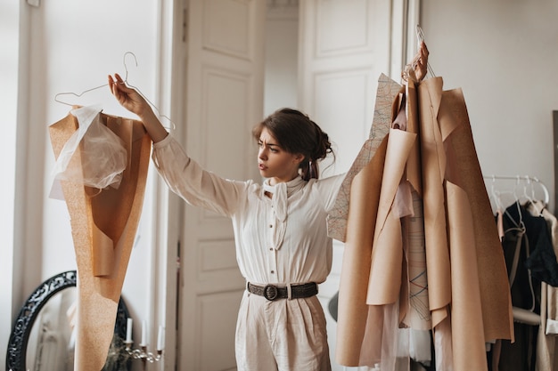 Foto gratuita donna che guarda pensierosa i suoi modelli di abbigliamento