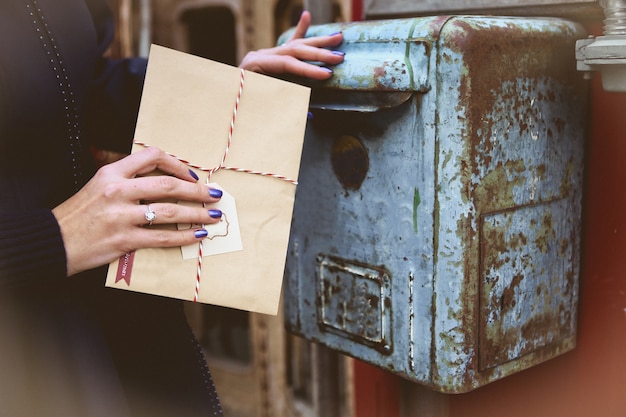 женщина бросает конверт Деда Мороза в старом старинном почтовом ящике