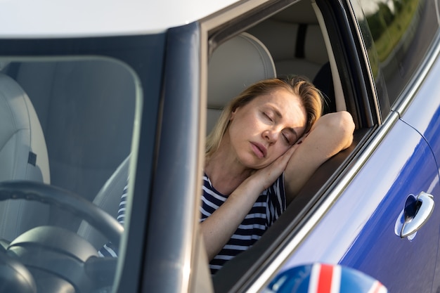 前席で寝るのにうんざりしている女性車でお昼寝休憩中の女性旅行 Premium写真