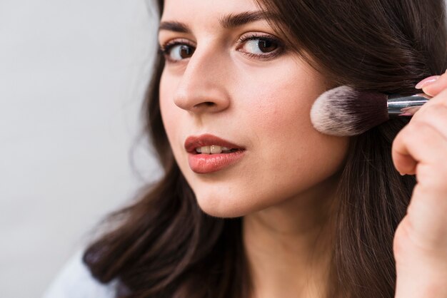 Woman touching cheek by powder brush