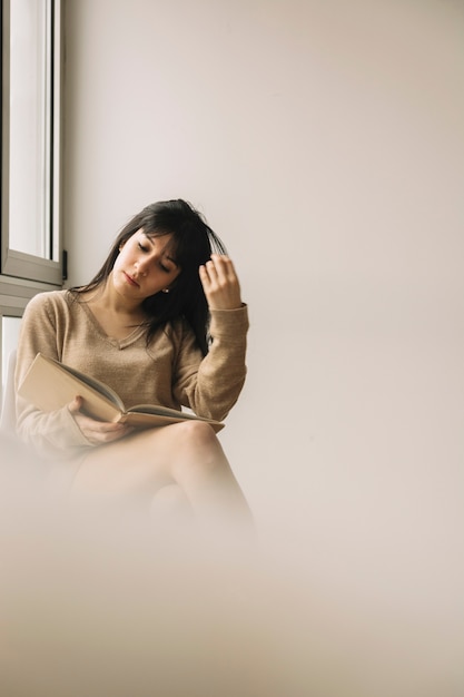 Free Photo woman touching hair while reading