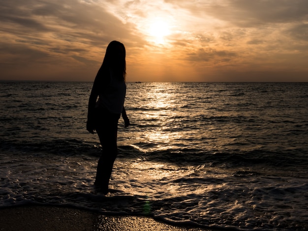 Woman tourist looking at sunset at sea. Relaxation at the sea