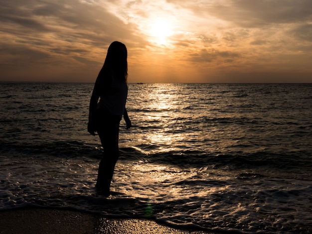 Женщина-турист, глядя на закат на море. Отдых на море