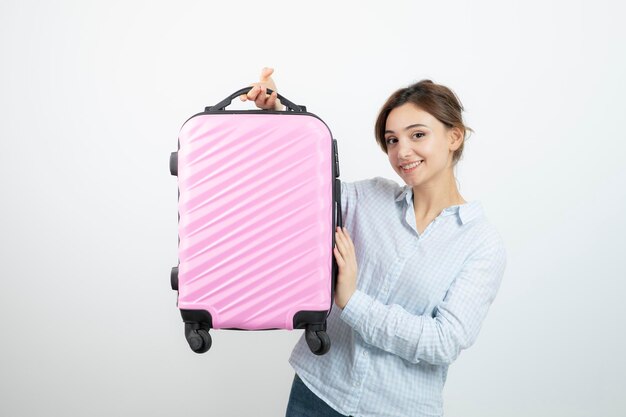 Woman tourist standing and holding pink travel suitcase . High quality photo