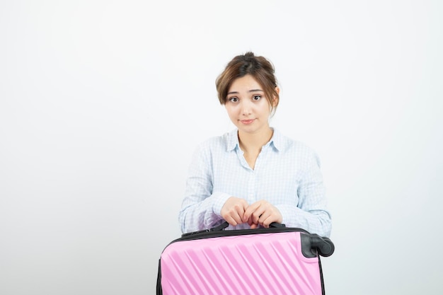 Woman tourist standing and holding pink travel suitcase . High quality photo