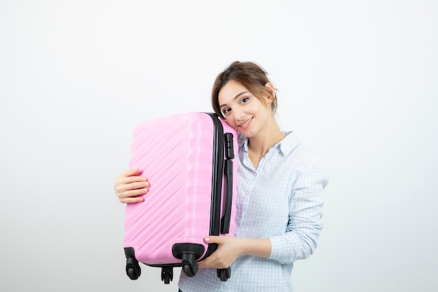 Woman tourist standing and holding pink travel suitcase . High quality photo