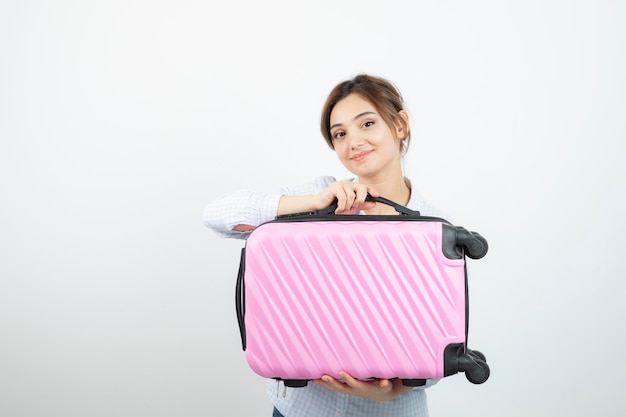 Woman tourist standing and holding pink travel suitcase . High quality photo