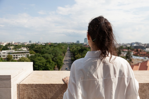 Woman tourist standing on tower terrace enjoying summer vacation