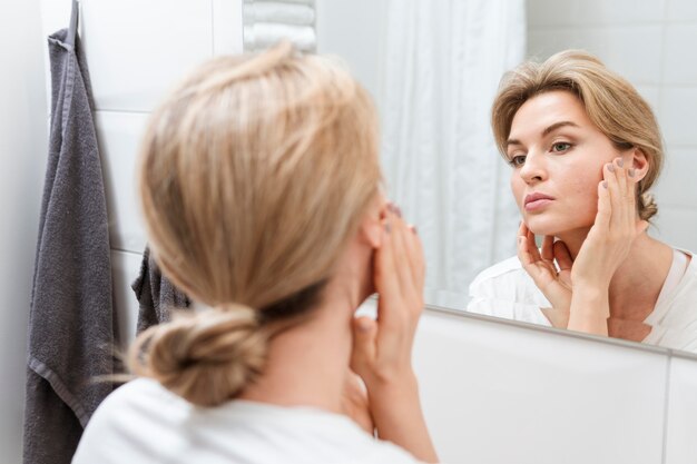 Woman in towel checking herself in the mirror