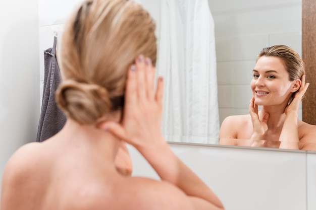 Woman in towel checking herself in the mirror