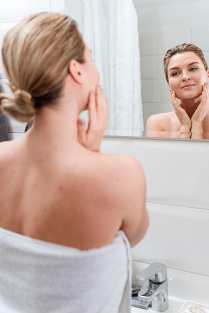Woman in towel looking into the mirror