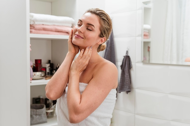 Free photo woman in towel touching her face