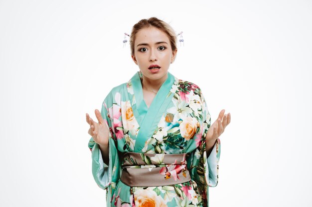 Woman in traditional japanese kimono confused and displeased raising arms in indignation and displeasure on white