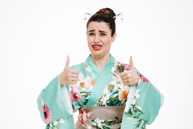 Foto gratuita donna in kimono tradizionale giapponese confusa che mostra i panni su bianco