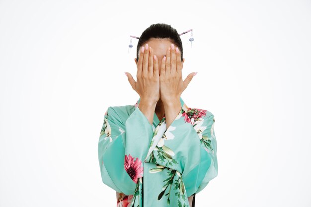 Woman in traditional japanese kimono coning face with arms on white