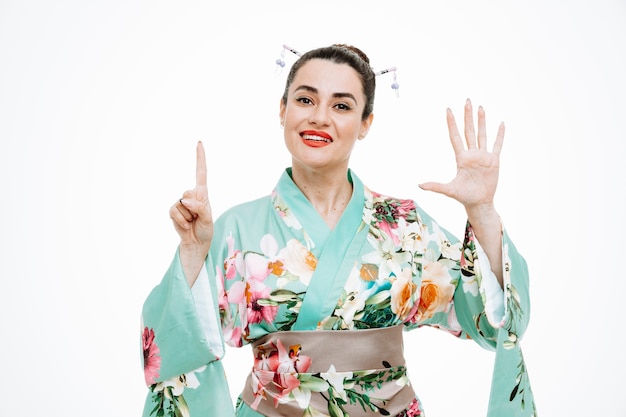 Женщина в традиционном японском кимоно счастлива и позитивна, показывая номер шесть пальцами на белом