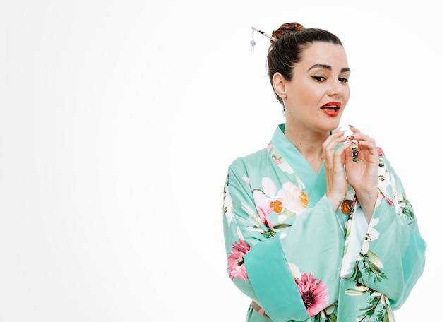 Woman in traditional japanese kimono looking aside happy and surprised smiling being intrigued on white