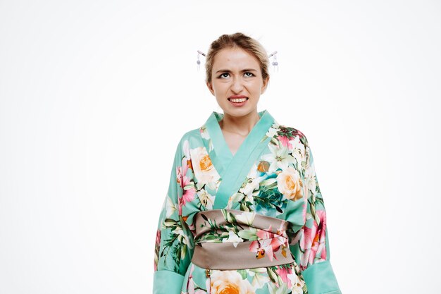 Woman in traditional japanese kimono looking up annoyed and irritated making wry mouth on white
