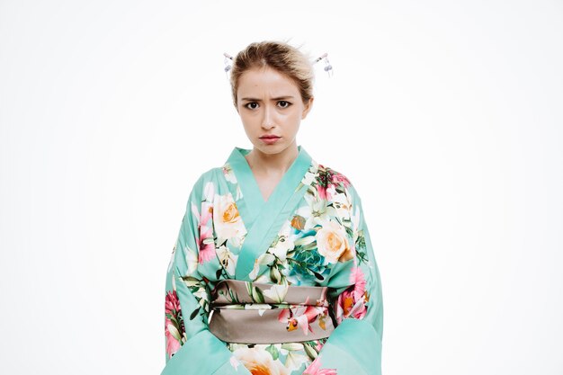 白に怒っている眉をひそめている顔を持つ伝統的な日本の着物の女性