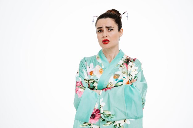 Woman in traditional japanese kimono with skeptic expression with arms crossed on white