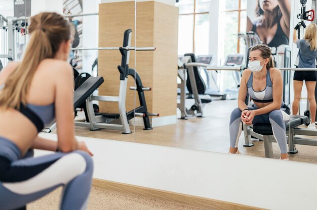 Woman training at the gym during the pandemic with medical mask