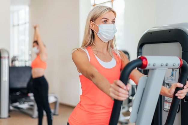 Woman training at the gym with mask