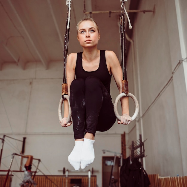 Тренировка женщины на кольцах гимнастики