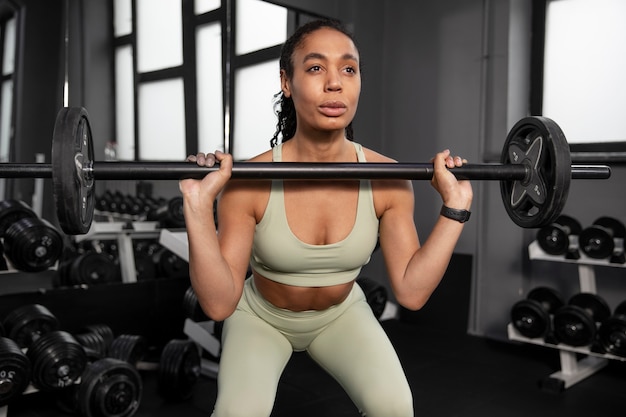 Foto gratuita allenamento donna per sollevamento pesi in palestra