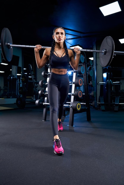 Woman training with barbell on shoulders