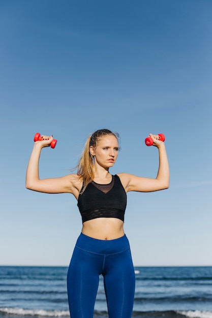 Woman training with dumbbells at the beach