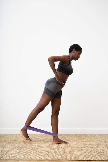 Woman training with elastic band full shot