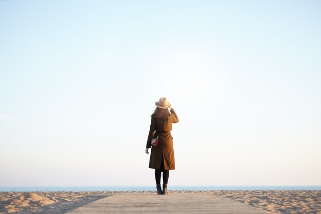 женщина путешественник, наслаждаясь видом на спокойное море осенью или весной верхней одежды, глядя вдаль.