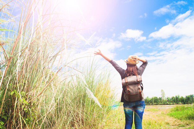 女性旅行者は手を押して、草や青空の畑で呼吸、散歩旅行のコンセプト、テキストのスペース