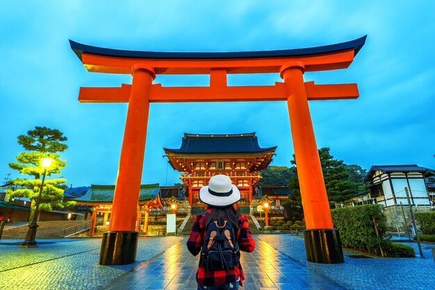 Woman traveler with backpack at fushimi inari taisha shrine in Kyoto, Japan.