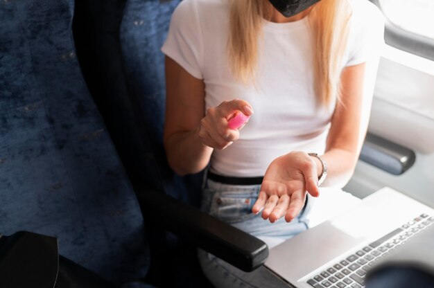 Woman traveling by train using hand sanitizer spray for protection