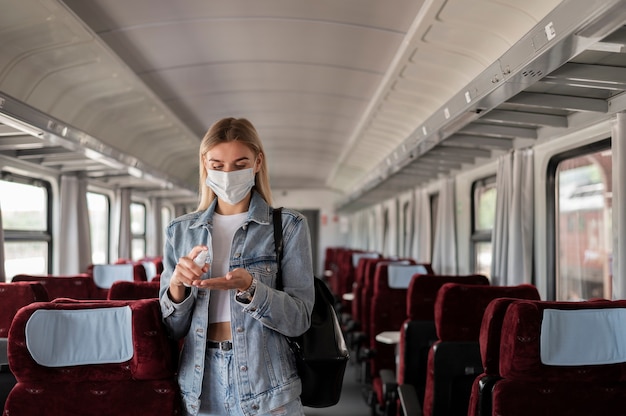 Woman traveling by train using hand sanitizer spray for protection