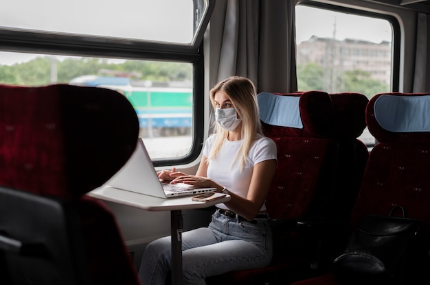 電車で旅行し、ラップトップで作業している女性