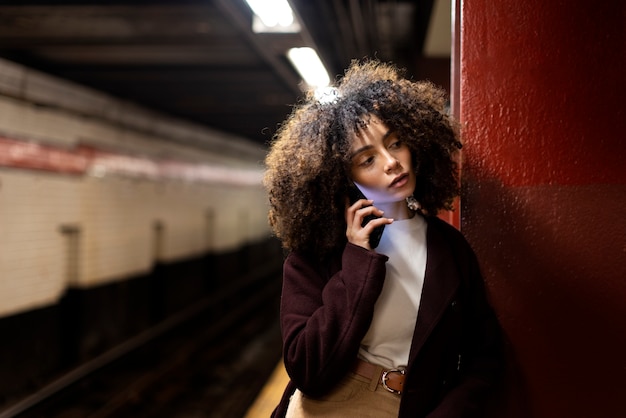Женщина едет на метро по городу и разговаривает по телефону