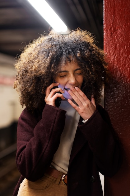 Woman traveling with the subway in the city while yawning and talking on phone