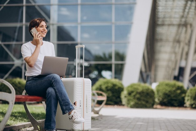 空港で旅行し、コンピューターで作業している女性