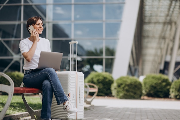 Женщина путешествует и работает на компьютере в аэропорту