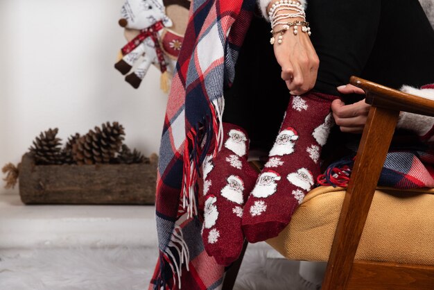 Woman trying on Christmas socks near the fireplace. 