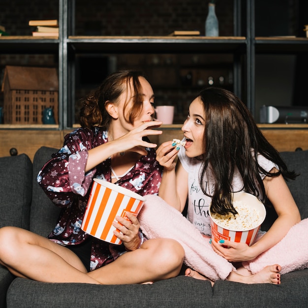 Woman trying to grab popcorn from her friend's hand