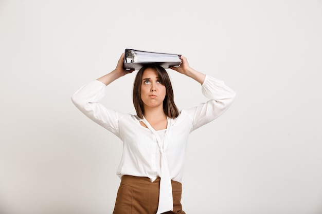 Бесплатное фото Женщина пытается держать на голове стопки документов