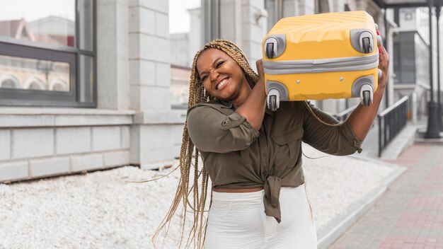 Woman trying to lift a heavy luggage on her shoulder