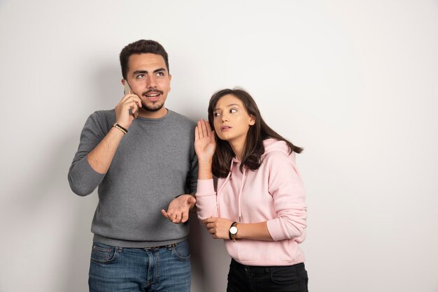 Woman trying to listen what boyfriend talking in telephone.