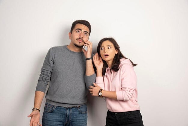 Free photo woman trying to listen what boyfriend talking in telephone.