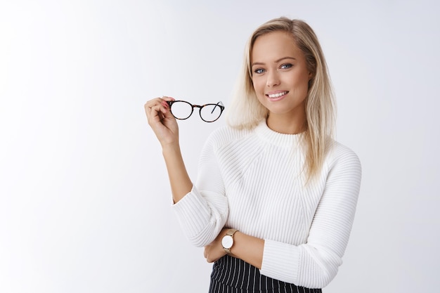 Free photo woman trying new glasses in store picking right frame fits style posing over white background confident and satisfied smiling pleased holding eyewear in arm feeling self-assured and successful.