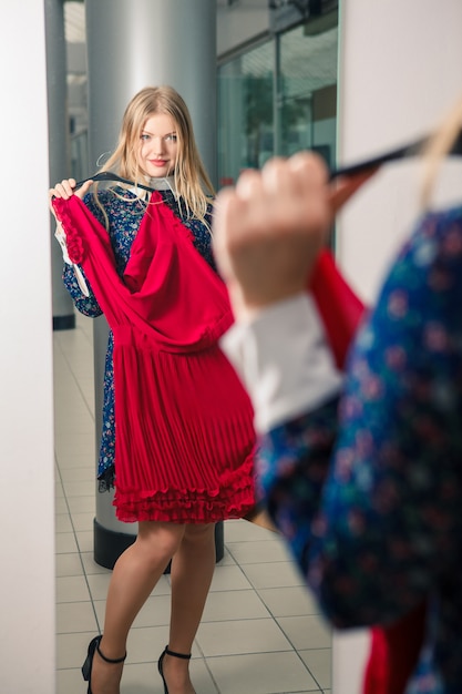 무료 사진 의류 쇼핑 빨간 드레스를 시도하는 여자.